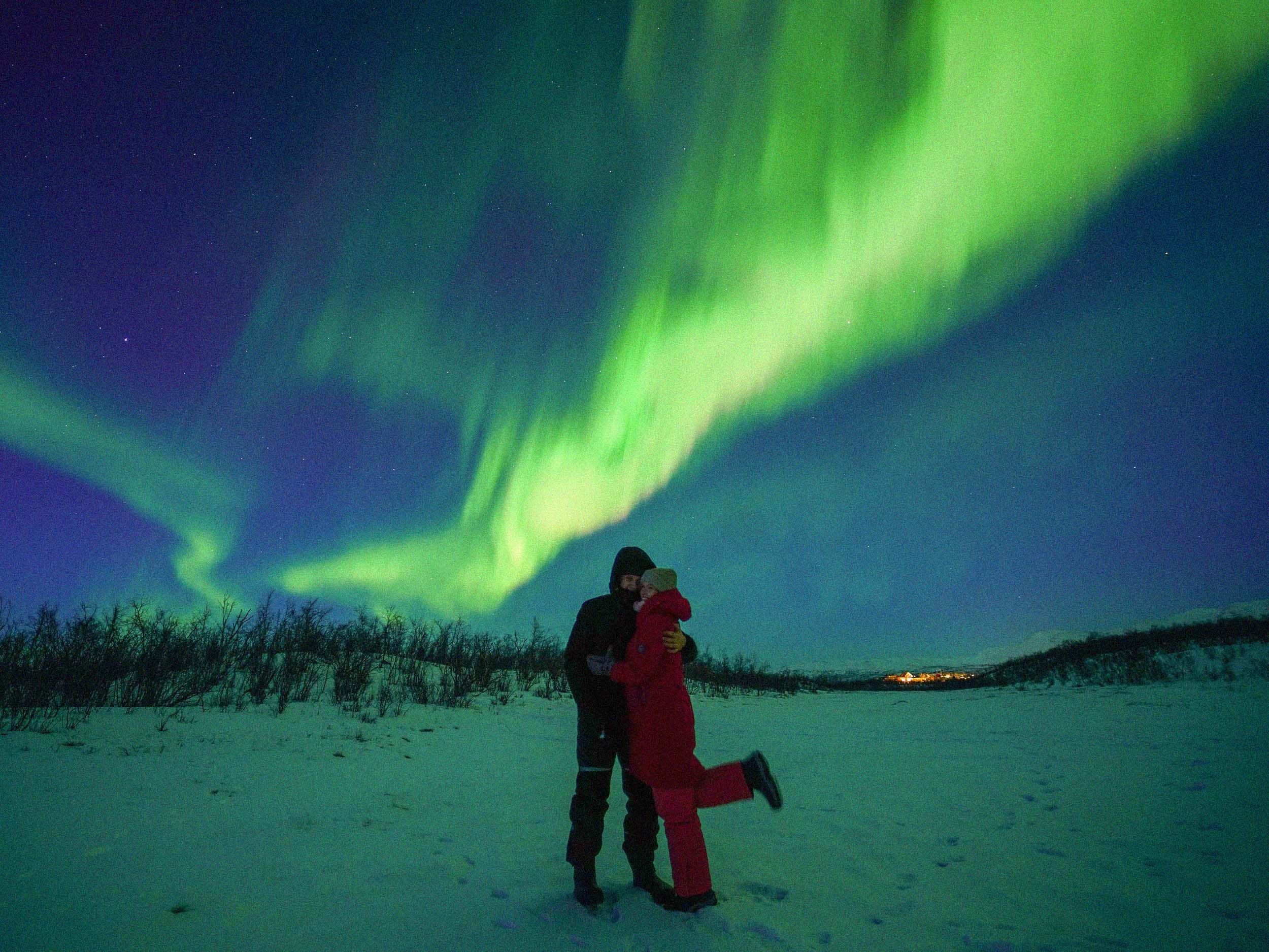 Happy couple hugging bellow an aurora in the sky
